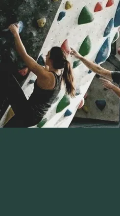 Monitor ayudando a una escaladora en su primer curso