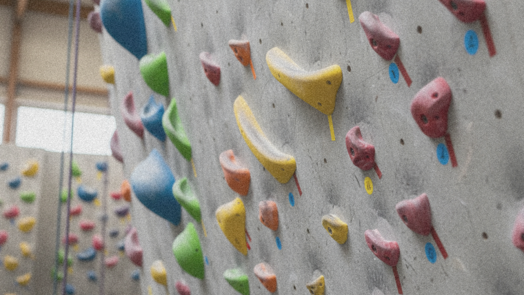 Primer plano de presas de escalada de colores en un muro de boulder, marcando los grados